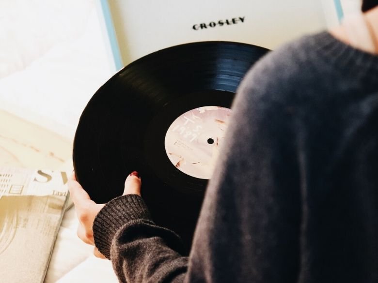 over shoulder of woman holding a warped record in her hands